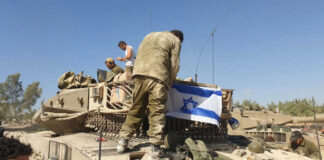 Soldiers on tank with Israeli flag in open field