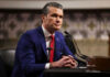 Woke Promotions Purge Rocks Pentagon Man in blue suit speaking at a microphone