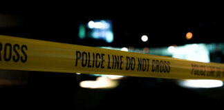 Yellow police line tape at night with blurred city lights