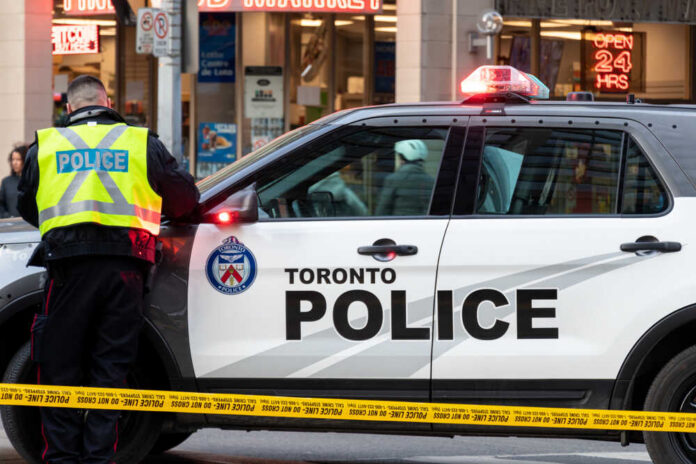 Toronto,,Ontario,-,December,28,,2019:,Toronto,Police,Officer,Writing Police officers in high-visibility jackets with radios.