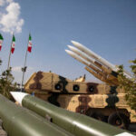 Iran Hits Kuwait, Bahrain in Missile Barrage Military missiles displayed outdoors with Iranian flags in the background
