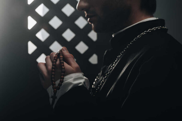 Partial,View,Of,Catholic,Priest,Holding,Wooden,Rosary,Beads,Near