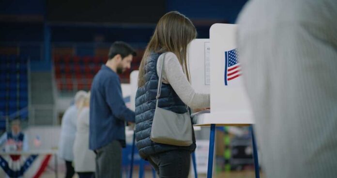 Caucasian,Female,Voter,Comes,With,Bulletin,To,Voting,Booth.,American A person casting their vote at a polling station