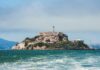 View of Alcatraz Island with buildings and lighthouse surrounded by water