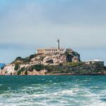 Alligator Alcatraz Closes—Mystery Deepens View of Alcatraz Island with buildings and lighthouse surrounded by water