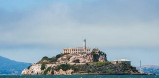 View of Alcatraz Island with buildings and lighthouse surrounded by water