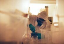 Scientist in protective gear mixing substance in a lab