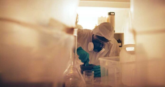 Scientist in protective gear mixing substance in a lab