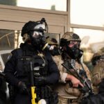 Backlash Forces ICE Training Overhaul Police officers in tactical gear wear gas masks during a crowd control operation