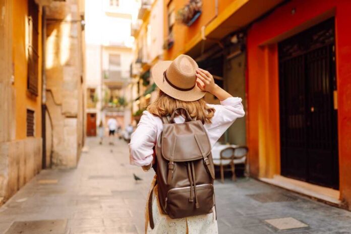 Traveler with hat and backpack facing a grand fountain and arch