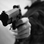 Close-up of a person holding a handgun in a threatening manner