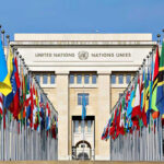 UN Conclave Begins — Stakes Are Huge United Nations building with numerous national flags outside.