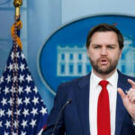 Tariff Shock: Vance Ditches Free-Market Playbook Man speaking at podium with US flag behind