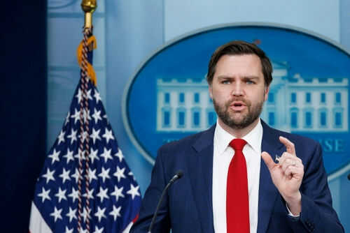 Man speaking at podium with US flag behind