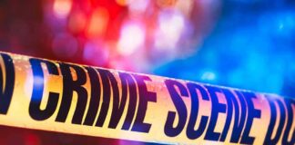 Crime scene tape with blurred emergency lights in background