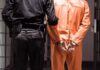 El Salvador’s Mega Terms—Justice or Theater? Prisoner in orange jumpsuit handcuffed with guard standing beside