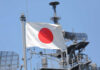 Silhouettes of soldiers saluting the Japanese flag against a sunset