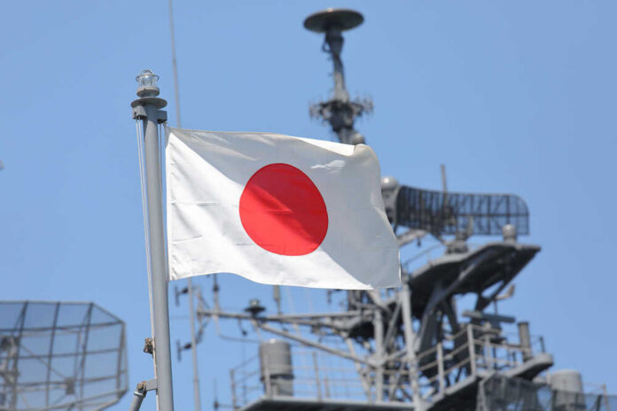 Silhouettes of soldiers saluting the Japanese flag against a sunset