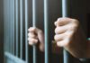 hands gripping prison bars