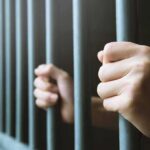 hands gripping prison bars