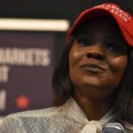 Bot War Explodes — Proof Still Missing woman in a red cap holding a microphone