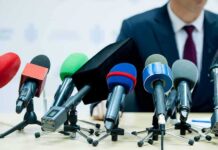 microphones clustered on a table at a press conference