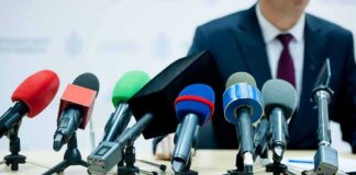 microphones clustered on a table at a press conference