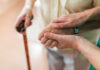 Two hands clasped together, one elderly and one younger, symbolizing support