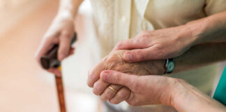 Two hands clasped together, one elderly and one younger, symbolizing support