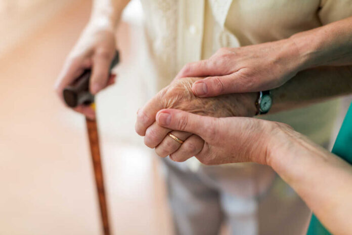 Nurse,Consoling,Her,Elderly,Patient,By,Holding,Her,Hands Two hands clasped together, one elderly and one younger, symbolizing support