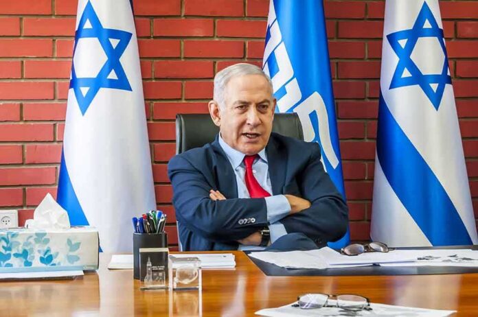 shutterstock_1564752907 man in suit seated at desk with Israeli flags
