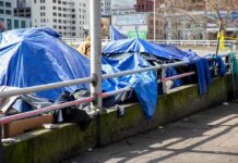 Massive Power Shift On Homelessness Tents covered with blue tarps along a city sidewalk