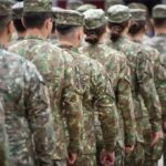 Soldiers in camouflage uniforms standing in formation from behind