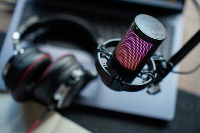 Close,Up,Of,Podcast,Microphone,Above,Laptop,,Headphones,,And,Notebook