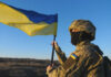 Zelenskyy Meeting Triggers Sudden Flip Soldier holding a Ukrainian flag outdoors