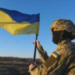 Soldier holding a Ukrainian flag outdoors
