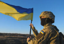 Soldier holding a Ukrainian flag outdoors