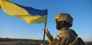 Soldier holding a Ukrainian flag outdoors