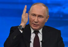 man in suit speaking with raised hand