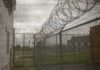 1,250 Men Next Door? Tiny Village Erupts Barbed wire on chain-link fence at a prison yard
