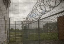 1,250 Men Next Door? Tiny Village Erupts Barbed wire on chain-link fence at a prison yard