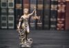 Lady Justice statue with scales in front of law books
