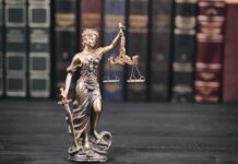 Texas Judges Torch Tainted Conviction Lady Justice statue with scales in front of law books