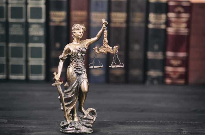 Lady Justice statue with scales in front of law books