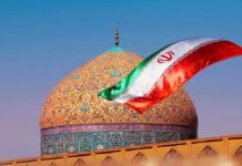 Iranian flag waves before an ornate mosque dome at sunset
