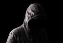 Hooded figure in shadow on black background