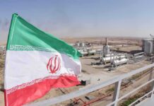 Iran flag over an oil and gas facility in a desert landscape