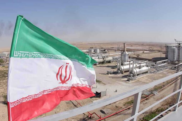 shutterstock_1227310843 Iran flag over an oil and gas facility in a desert landscape
