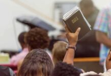 Hand holding a Bible in a crowded church service