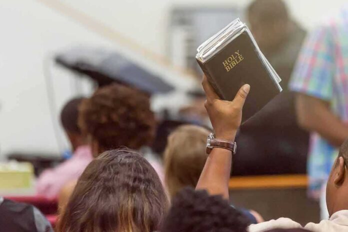 Hand holding a Bible in a crowded church service
